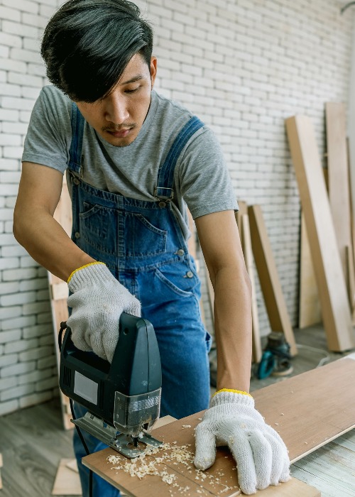 Carpenter doing his job in carpentry workshop. Portrait of adult carpenter teaching apprentice standing at table in workshop, copy space.