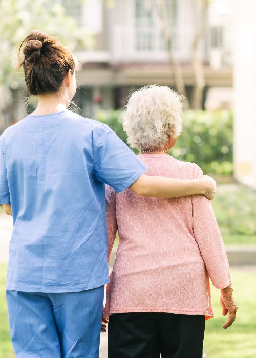 nurse caregiver support walking with elderly woman outdoor